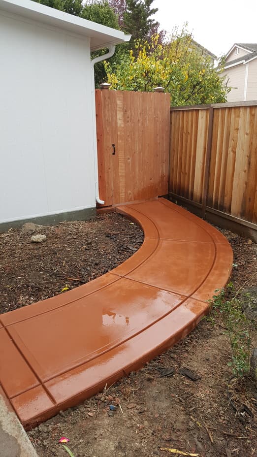 new winding concrete sidewalk in the backyard of a residential home